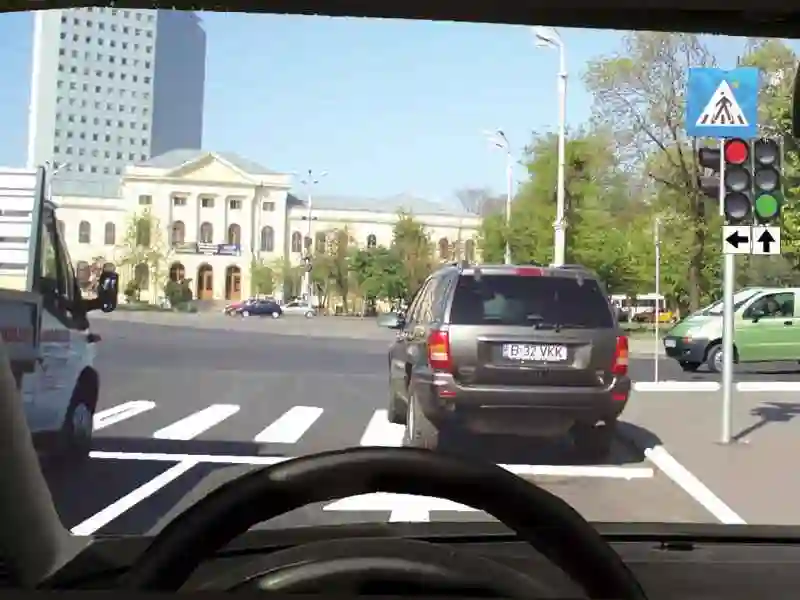 Imagine întrebare examen auto: Autovehiculul din fața dvs. traversează intersecția. Cum veți proceda?