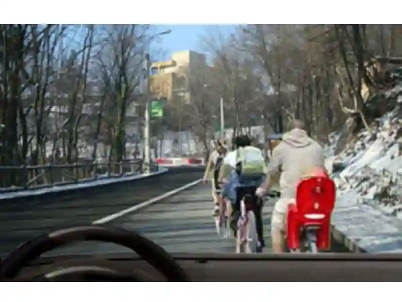 Imagine întrebare examen auto: Pentru a depăși acești bicicliști poți trece peste linia continuă?
